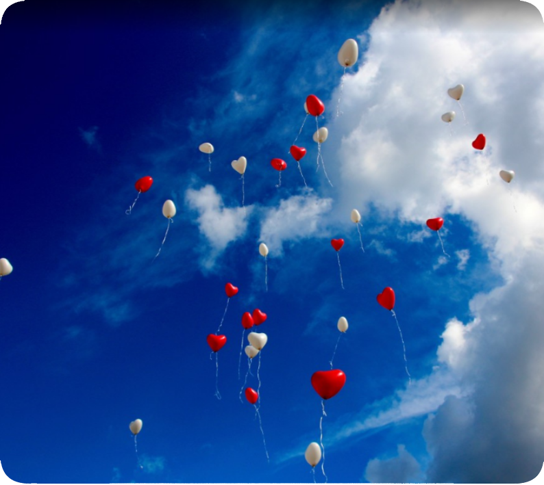 Ballons rouges en forme de cœur dans le ciel. Des ballons flottant dans le ciel bleu, dont certains rouges en forme de cœur, symbolisant l’amour et la légèreté.